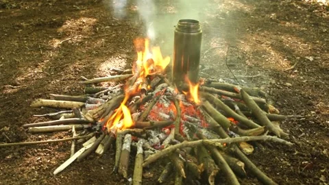 Boiling Water over the Campfire. Boiling Water in Metal Bottle for Survival Stock Footage 306871518