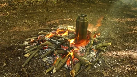 Boiling Water over the Campfire. Boiling Water in Metal Bottle for Survival Stock Footage 306871579