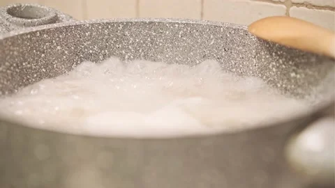 Boiling Water in the Pan Creates Steam with Wooden Spoon Stock Footage 145219647