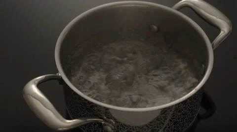 Boiling water in a pot on black electric stove Stock Footage 67990449