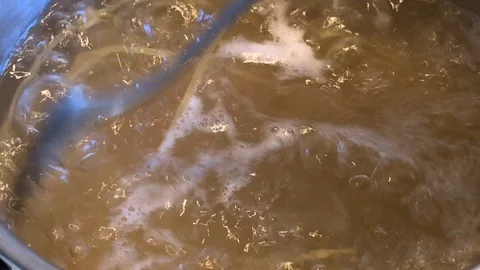 Boiling water in a pot with a fork mixing yellow spaghetti pasta Stock-Footage 85717906