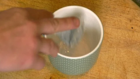 Boiling water is poured into a cup containing a tea bag Stock Footage 98980145