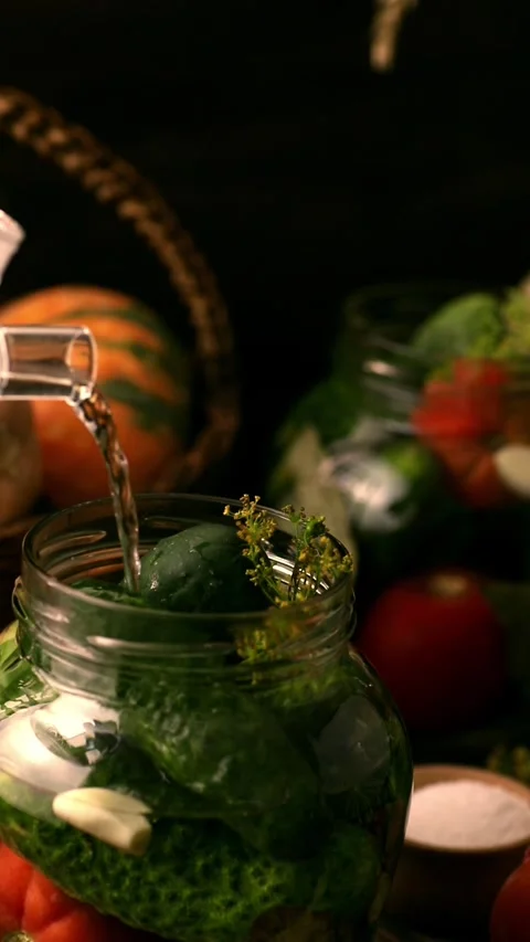 Boiling water is poured into a jar with cucumbers, tomatoes Stock Footage 291072913