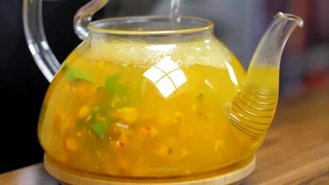 Boiling water is poured into a kettle with sea buckthorn, mint and berries Stock Footage 201092011