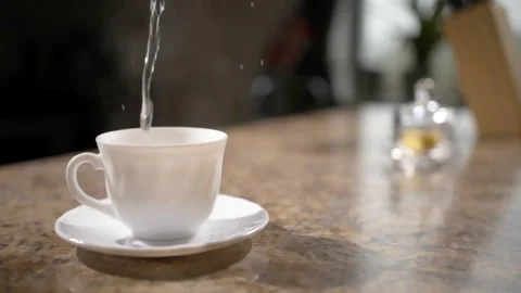 Boiling water poured into teacup in kitchen as camera pans around (slowmo) Stock Footage 162670115