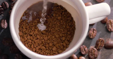 Boiling water is poured into a white cup on granules of instant coffee. Video stock 145193760