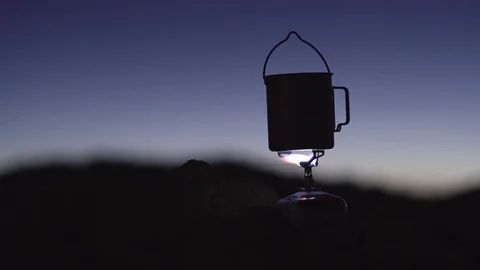 Boiling water in a titanium cup on a gas burner at night in the mountains Stock Footage 102372246