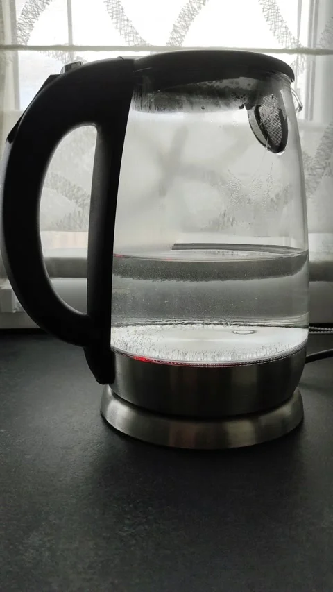 Boiling water in a transparent teapot on the kitchen table by the window Stock Footage 162621308