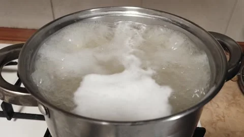Boiling White Starchy Foam in Stainless Steel Pot on Gas Stove Video stock 339084020