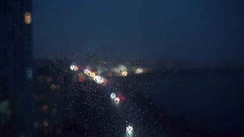 Bokeh of city lights through raindrops flowing down the glass. Stock Footage 198727133