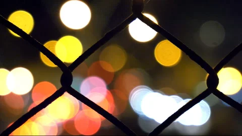 Bokeh lights of freeway traffic through chain link fence on freeway overpass. 스톡 동영상 170124716