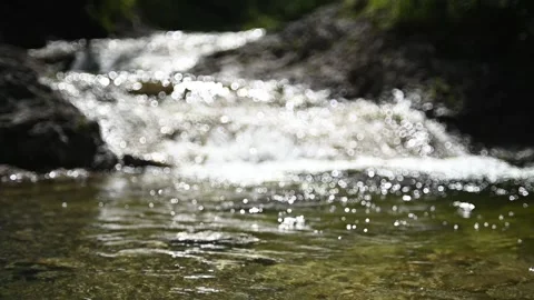 Bokeh of a mountain stream in back light (slow motion) Video stock 260845173