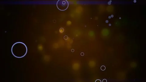 Bokeh particles float and glisten over dark background with depth of field. Stock Photos