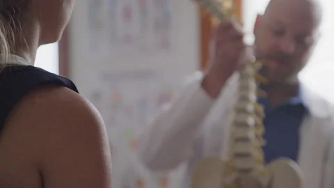 Bokeh Shot of a Chiropractor as He Explains the Function of the Spine 스톡 동영상 208758854