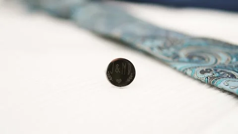 Bokeh shot of an engraved cuff link with initials on the piece Stock Footage 244321126