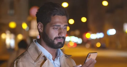 Bokeh shot of handsome man using smartphone mobile in city at night Stock Footage 161717714