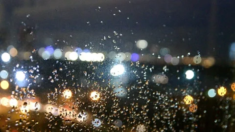 Bokeh of street lights viewed through a window with rain dropped Stock Footage 165389975