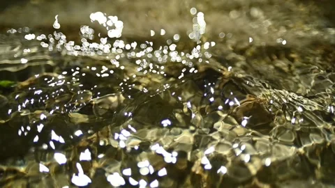 Bokeh of sunlight reflections on the water in a mountain riverbed (slow motion) Stockbeeldmateriaal 211746723
