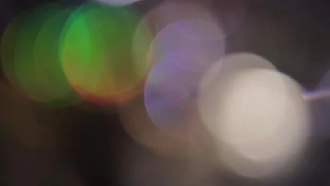 Bokeh video of large colored particles glowing in the dark Видео 318075661