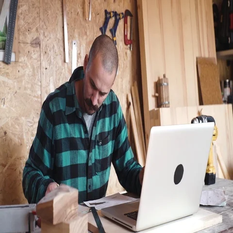 Bold carpenter with vintage moustache is using a laptop while working in the wor Stock Footage 69531757