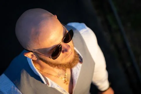 Bold Guy with a stylish beard and sunglasses on a blurred background during Stock Photos