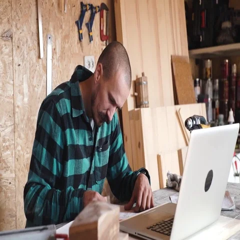 Bold with moustache young Carpenter Craftsman do drawing with laptop in his Stock Footage 69532460