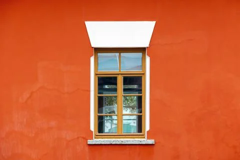 Bold orange wall frames a classic wooden window with glass panes. Photo textu Foto stock