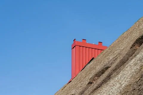 Bold Red Chimney on a Rustic Thatched Roof Under Blue Sky Stock Photos