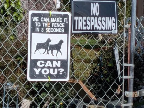 A bold security sign warning of fast guard dogs paired with a No Trespassing Stock Photos