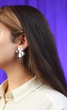 Bold silver bow earring on model with shiny sculptural design Stock Photos