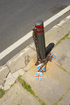 A bollard is chained to the sidewalk with three shield-shaped signs with th.. Foto stock