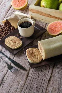 Bolo de rolo slice surrounded by cutlery, guava, cup and coffee beans (with c Stock Photos