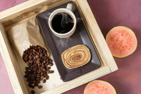 Bolo de rolo slice surrounded by guava, cup and coffee beans. Stock Photos