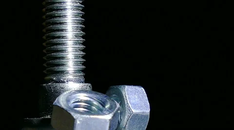 Bolt and three nuts rotates against  dark background. 4K  close up left side Stockbeeldmateriaal 61458162