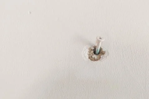A bolt is embedded in the white wall. Stock Photos