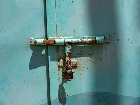 A bolt with a lock on a massive blue iron door. Stock-Fotos