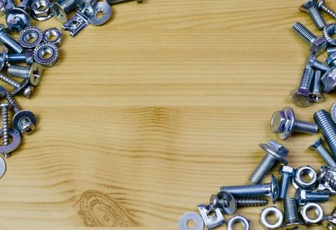 Bolts and nuts in the form of a frame against a wooden table background Stock Photos