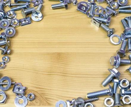 Bolts and nuts in the form of a frame against a wooden table background Stock Photos