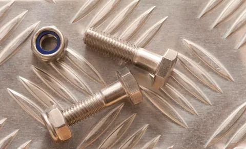 Bolts with nuts on metal surface Stock Photos