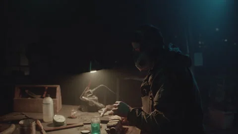 Bomb maker screwing something in the warehouse and using a blue jar Stock Footage 255999898