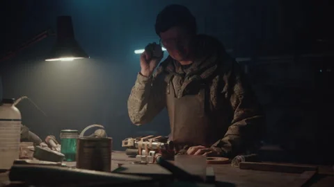 A Bomb maker taping a phone to an explosive Stock Footage 256013890