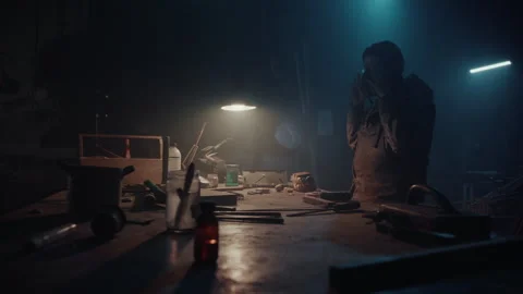 Bomb maker using some tools on the table in a an abandoned warehouse Stock Footage 256018216