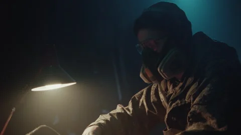 Bomb Maker in the Warehouse making a bomb with gas mask on Stock-Footage 256036955