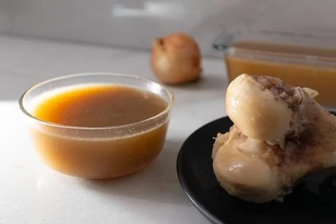 Bone Broth Preparation: Strained Stock from Chicken Leg for Nutritious Cookin Stock Photos