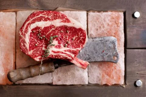 Bone In Rib Eye row Steak on pieces of salt Stock Photos