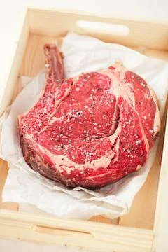 Bone-in Rib eye Steak steak on paper and wooden table Stock Photos
