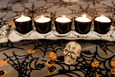 A bone with tea lights on it, skulls in the foreground and Halloween trim Stock Photos
