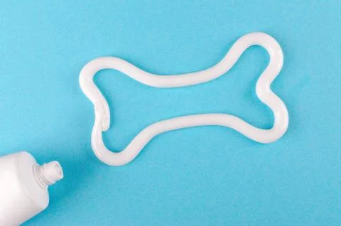 A bone from white toothpaste, animal teeth care concept, on blue background Stock Photos