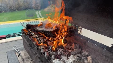 Bones with bone fat are cooked on a grill grate over hot coals and lit with a Stock Footage 319483884