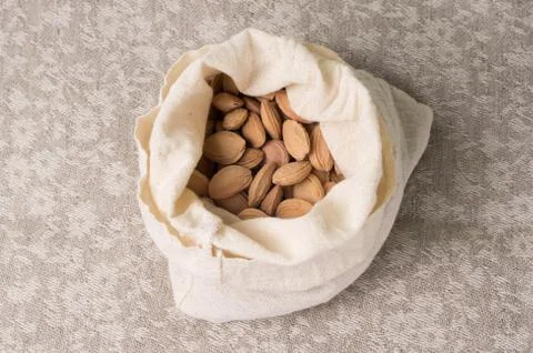 Bones of a plum in a canvas bag on the background of a linen gray tablecloth Foto stock